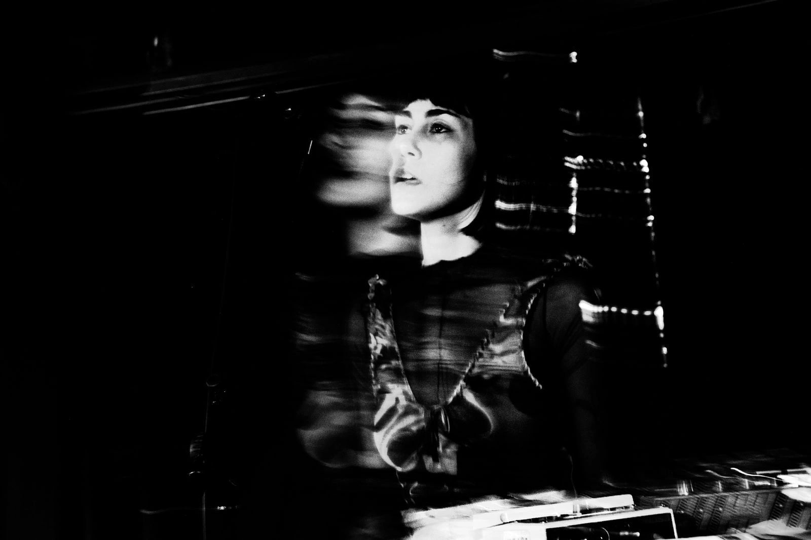 A black and white photo of Emily Zurowski on stage - the photo has special effects applied and is slightly blurred